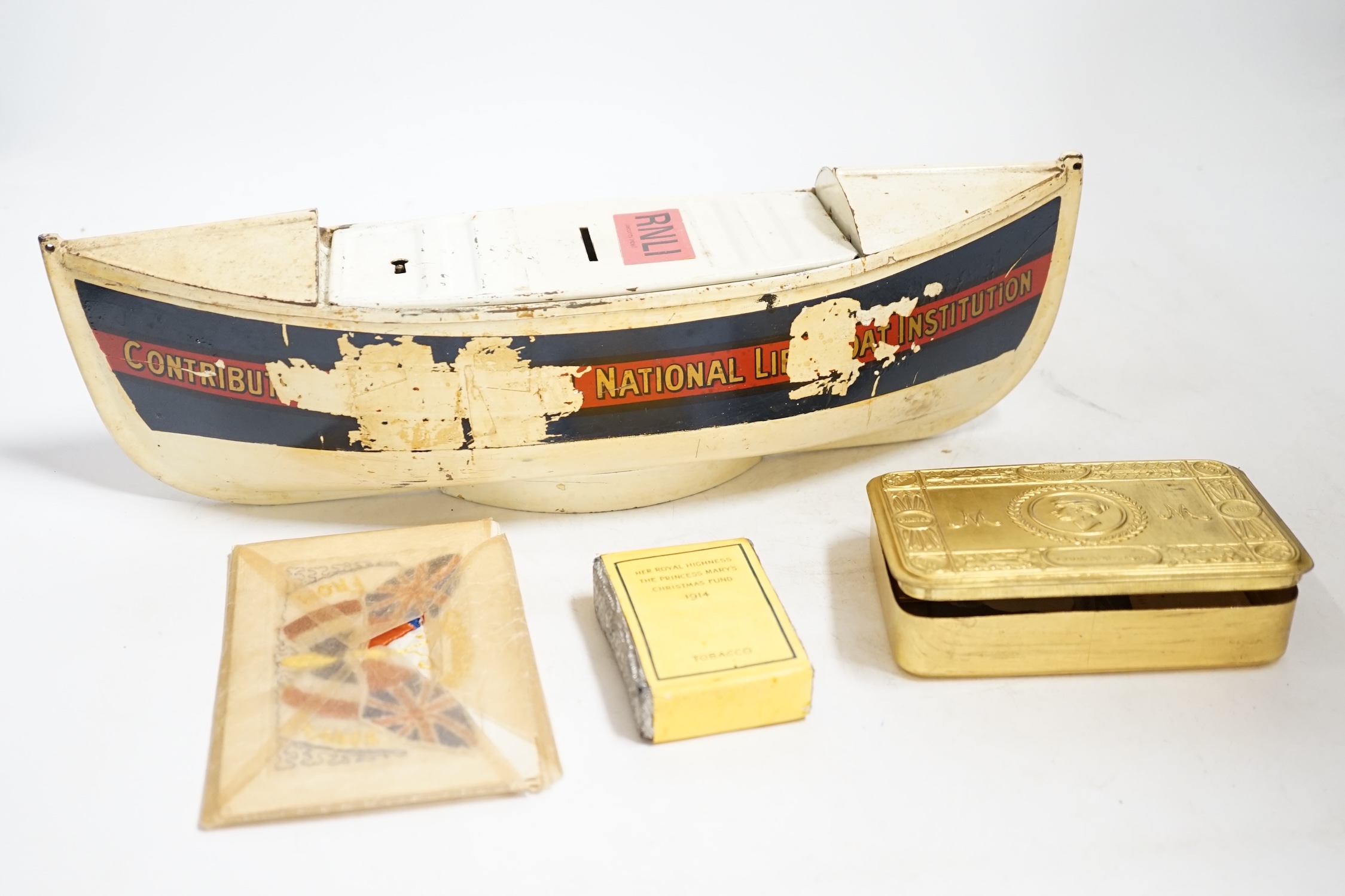 An RNLI sheet metal collecting box in the form of a lifeboat, together with a First World War Princess Mary Christmas tin containing the original tobacco, greetings card, photograph, and other items, plus two early 20th